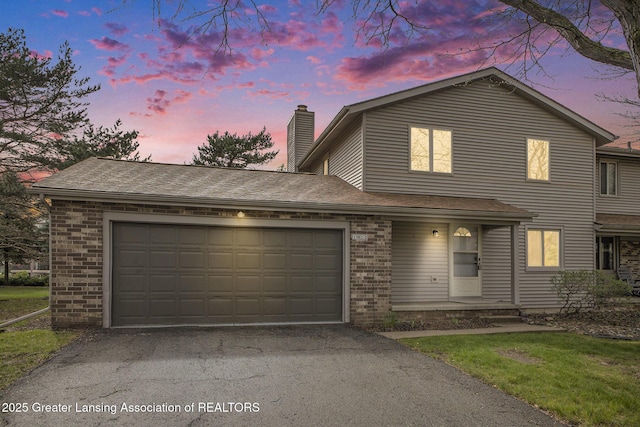traditional home with brick siding, driveway, a chimney, and an attached garage