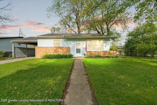 view of front of house featuring a carport, driveway, brick siding, and a chimney