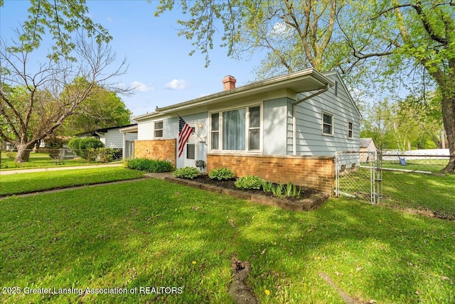 view of front of home featuring a chimney, brick siding, and a gate