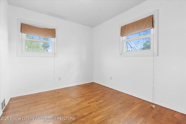 empty room featuring healthy amount of natural light, light wood-style floors, and baseboards