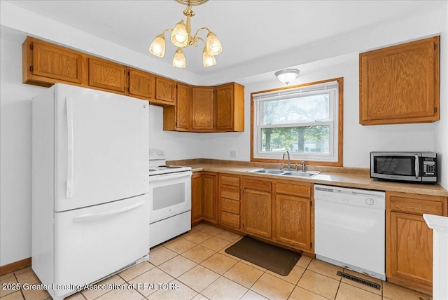 kitchen with white appliances, a sink, a chandelier, brown cabinets, and light countertops