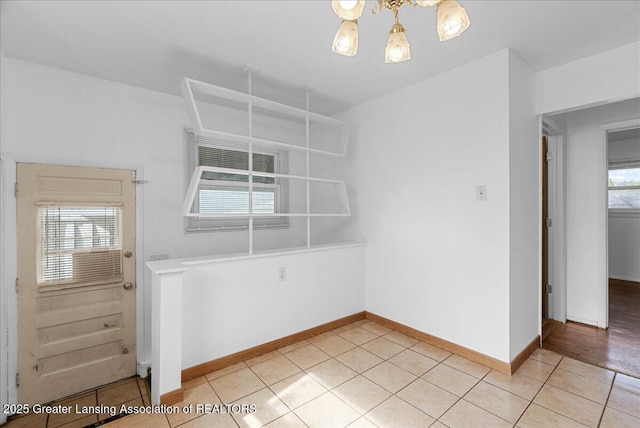 unfurnished dining area with a chandelier, light tile patterned floors, and baseboards
