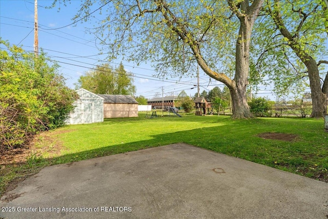 view of green lawn featuring a playground, a shed, a patio, and an outdoor structure
