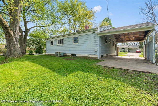 rear view of house with a lawn, a chimney, and an attached carport