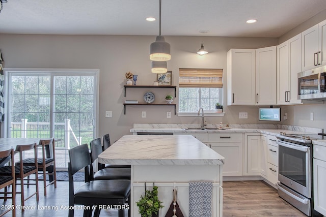 kitchen with stainless steel appliances, a sink, recessed lighting, light wood-style floors, and white cabinetry