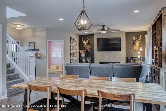 dining space with a fireplace, stairs, wood finished floors, recessed lighting, and ceiling fan