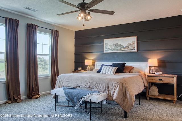 carpeted bedroom featuring baseboards, ceiling fan, and a textured ceiling
