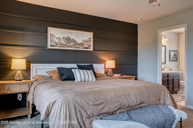 bedroom featuring carpet flooring, connected bathroom, a sink, and baseboards