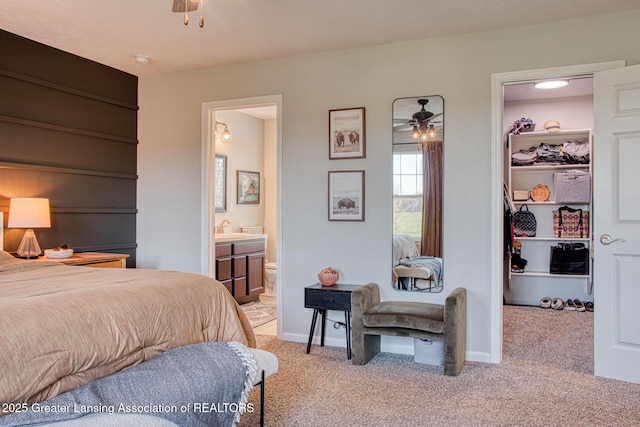 bedroom with a walk in closet, light carpet, a sink, a closet, and ensuite bath