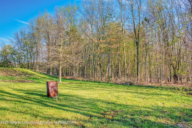 view of grassy yard featuring a forest view