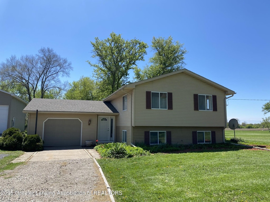 split level home featuring an attached garage, concrete driveway, and a front yard
