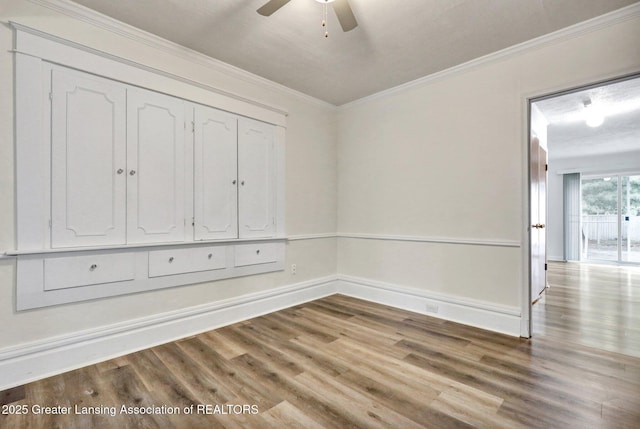 unfurnished room with wood finished floors, crown molding, ceiling fan, and baseboards