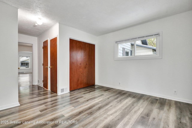 unfurnished bedroom featuring a closet, wood finished floors, and baseboards