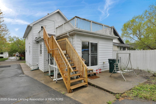 rear view of property featuring fence, stairs, and a patio area