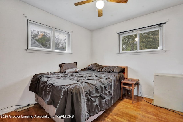 bedroom featuring wood finished floors, baseboards, and a ceiling fan
