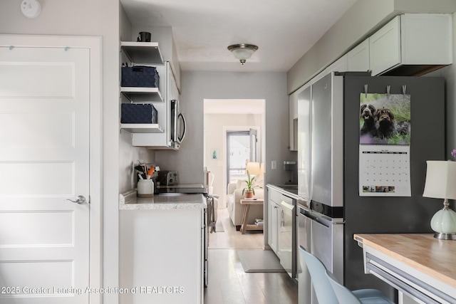 kitchen featuring stainless steel appliances, white cabinetry, and open shelves