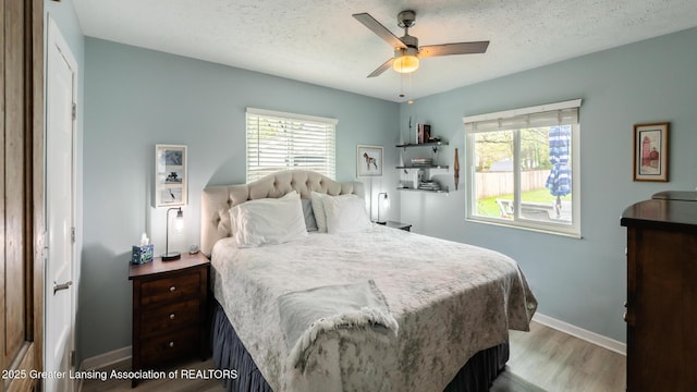 bedroom with wood finished floors, baseboards, a textured ceiling, and ceiling fan