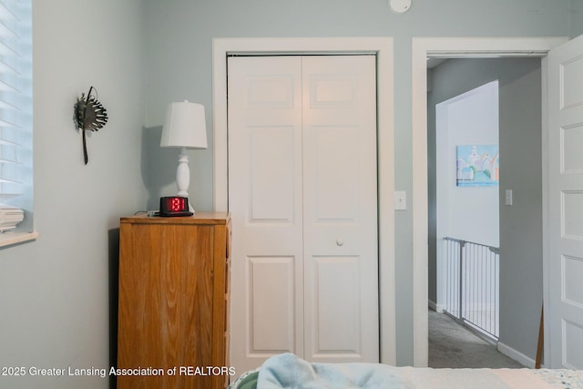 carpeted bedroom featuring a closet and baseboards