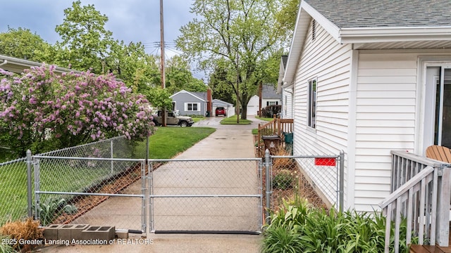 view of property exterior featuring a gate, roof with shingles, and fence