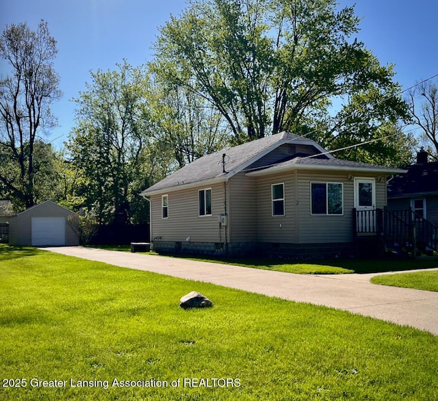 back of house featuring a detached garage, an outbuilding, a yard, and driveway