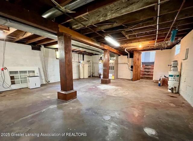 basement with concrete block wall, a water softener, and stairs
