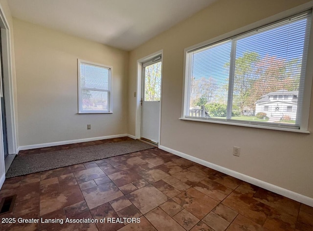 unfurnished room featuring baseboards and stone finish flooring