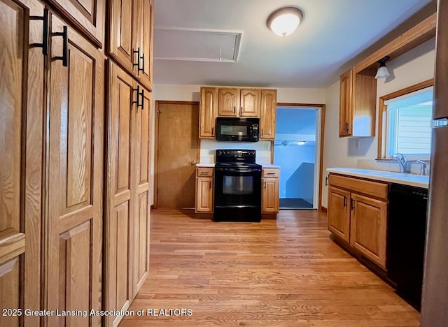 kitchen featuring black appliances, a sink, light countertops, and light wood-type flooring