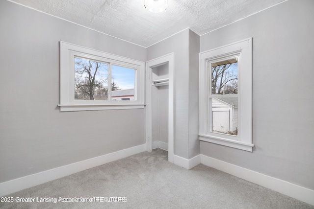 1416 Vermont Ave, Lansing, MI 48906 - unfurnished bedroom featuring carpet flooring, multiple windows, baseboards, a closet, and a textured ceiling