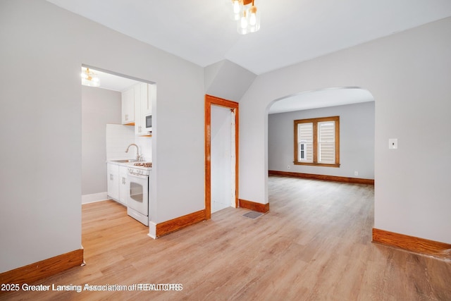 1416 Vermont Ave, Lansing, MI 48906 - spare room featuring arched walkways, light wood-type flooring, baseboards, and a sink