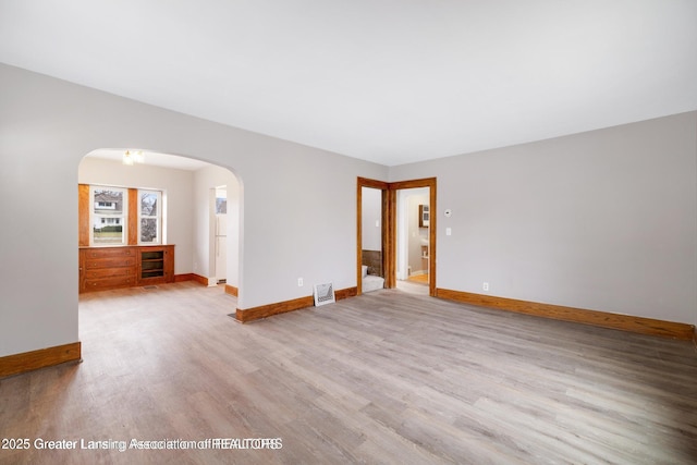 1416 Vermont Ave, Lansing, MI 48906 - spare room featuring arched walkways, wood finished floors, and baseboards