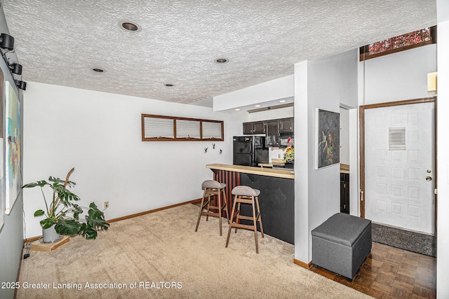 5431 Wild Oak Dr, East Lansing, MI 48823 - kitchen with freestanding refrigerator, a kitchen bar, a peninsula, baseboards, and light countertops