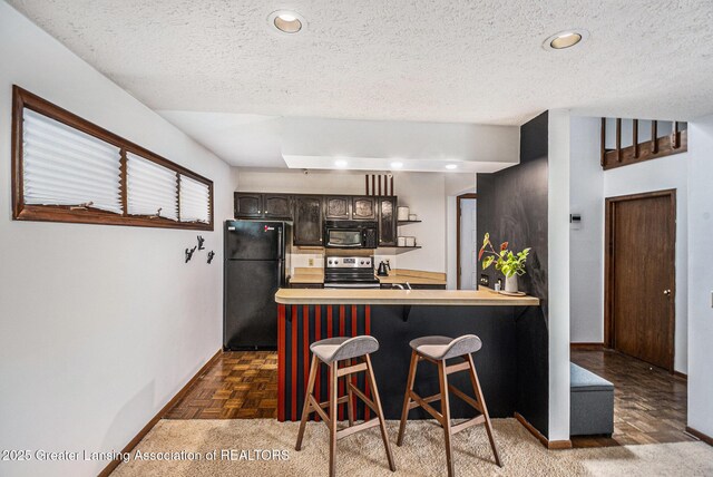 5431 Wild Oak Dr, East Lansing, MI 48823 - kitchen featuring black appliances, light countertops, a breakfast bar, baseboards, and a textured ceiling