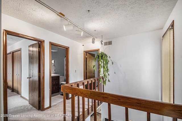 5431 Wild Oak Dr, East Lansing, MI 48823 - hall featuring light colored carpet, a textured ceiling, and an upstairs landing