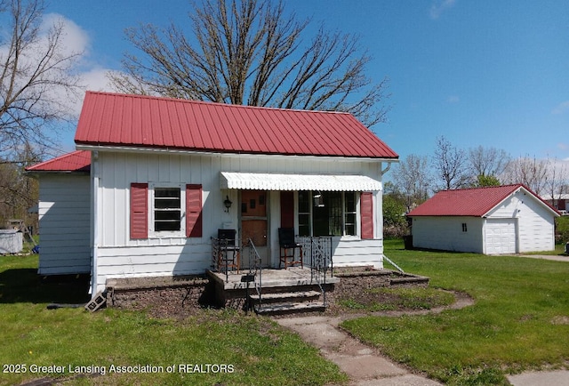 411 Ely St, Alma, MI 48801 - view of front of house featuring an outbuilding, a front lawn, metal roof, a garage, and a porch