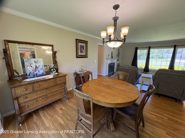 108 S Center St, Eaton Rapids, MI 48827 - dining space featuring ornamental molding, wood finished floors, a chandelier, and a fireplace with flush hearth