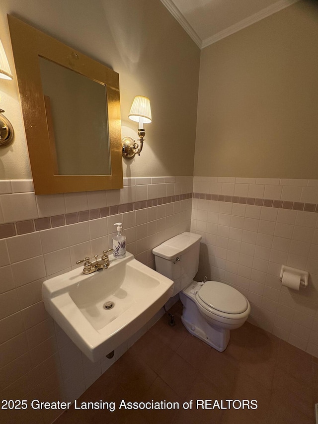 108 S Center St, Eaton Rapids, MI 48827 - half bath with ornamental molding, toilet, a sink, tile walls, and a wainscoted wall