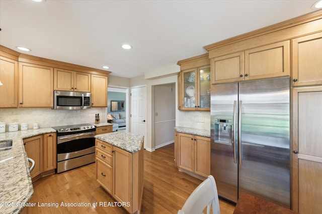 kitchen with stainless steel appliances, tasteful backsplash, light wood-type flooring, light stone countertops, and recessed lighting
