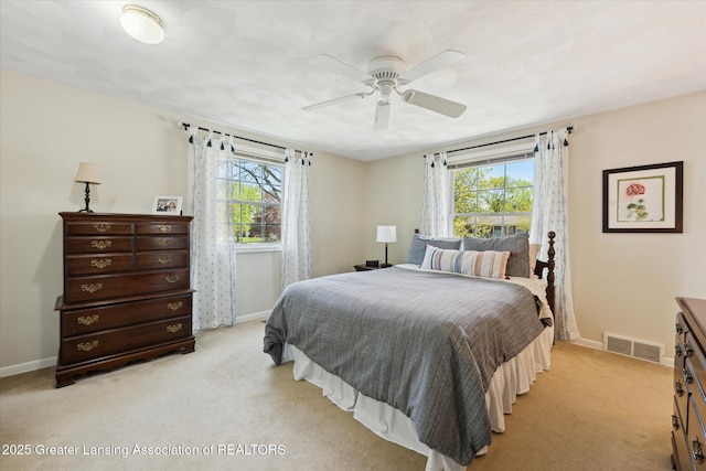bedroom with light colored carpet, baseboards, multiple windows, and a ceiling fan