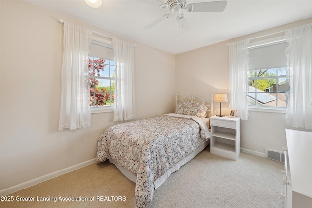 carpeted bedroom featuring multiple windows, baseboards, and ceiling fan