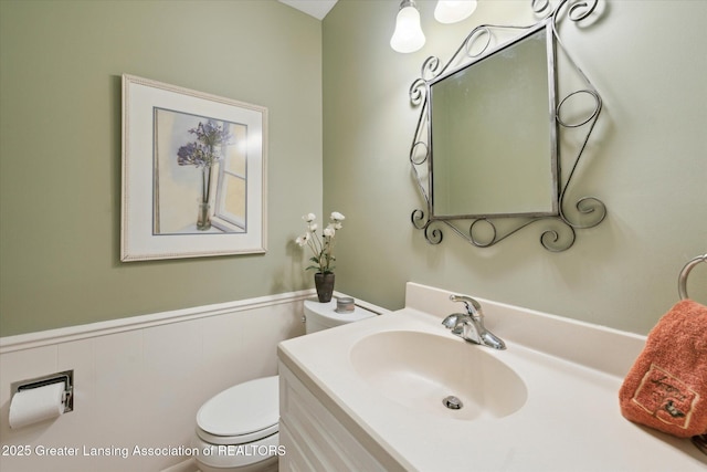 bathroom with toilet, vanity, and wainscoting