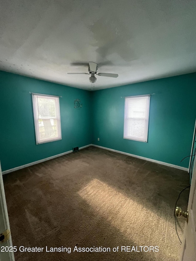 carpeted empty room featuring plenty of natural light, a ceiling fan, and baseboards