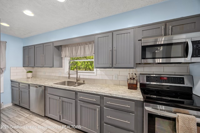 5364 Drumheller Rd, Bath, MI 48808 - kitchen with stainless steel appliances, gray cabinetry, a sink, tasteful backsplash, and a textured ceiling