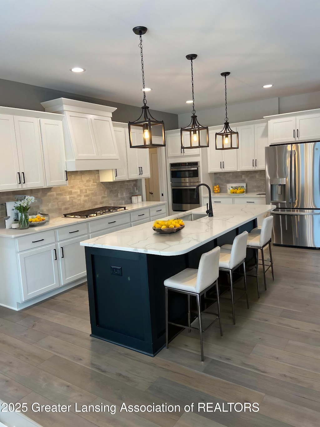 6120 Fresno Ln, East Lansing, MI 48823 - kitchen featuring appliances with stainless steel finishes, white cabinetry, tasteful backsplash, a spacious island, and a kitchen bar