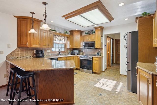 900 Oneida Woods Trl, Grand Ledge, MI 48837 - kitchen with stainless steel appliances, a peninsula, tasteful backsplash, light stone counters, and decorative light fixtures