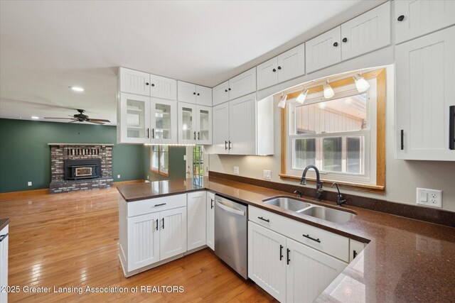 3415 W Needmore Hwy, Charlotte, MI 48813 - kitchen with stainless steel dishwasher, a sink, a peninsula, dark countertops, and white cabinets