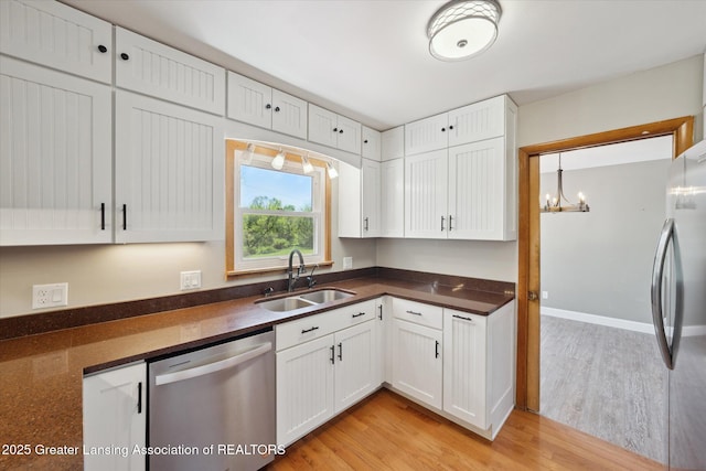 3415 W Needmore Hwy, Charlotte, MI 48813 - kitchen with stainless steel appliances, a sink, dark countertops, light wood-style floors, and white cabinetry