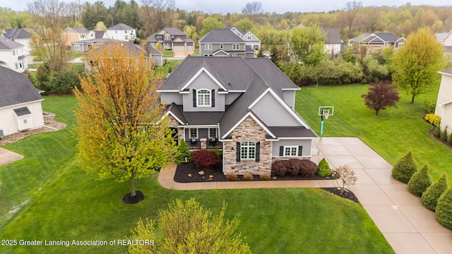 view of front facade featuring stone siding, a residential view, stucco siding, a front yard, and a shingled roof