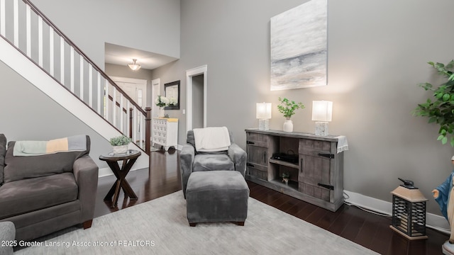 living area with wood finished floors, stairs, baseboards, and a high ceiling