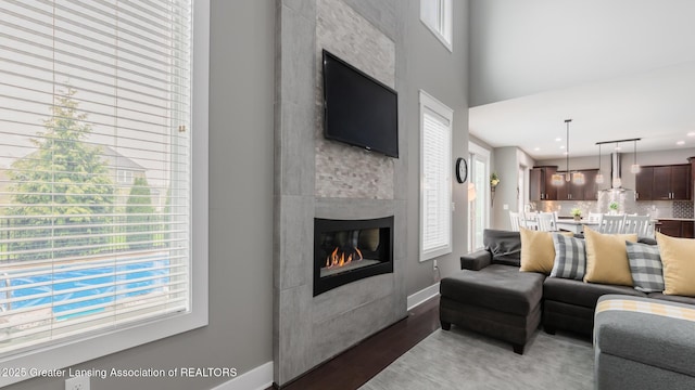 living area featuring wood finished floors, a fireplace, baseboards, and recessed lighting