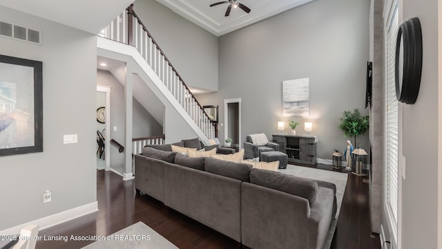 living room featuring ceiling fan, dark wood-style floors, baseboards, stairs, and healthy amount of natural light